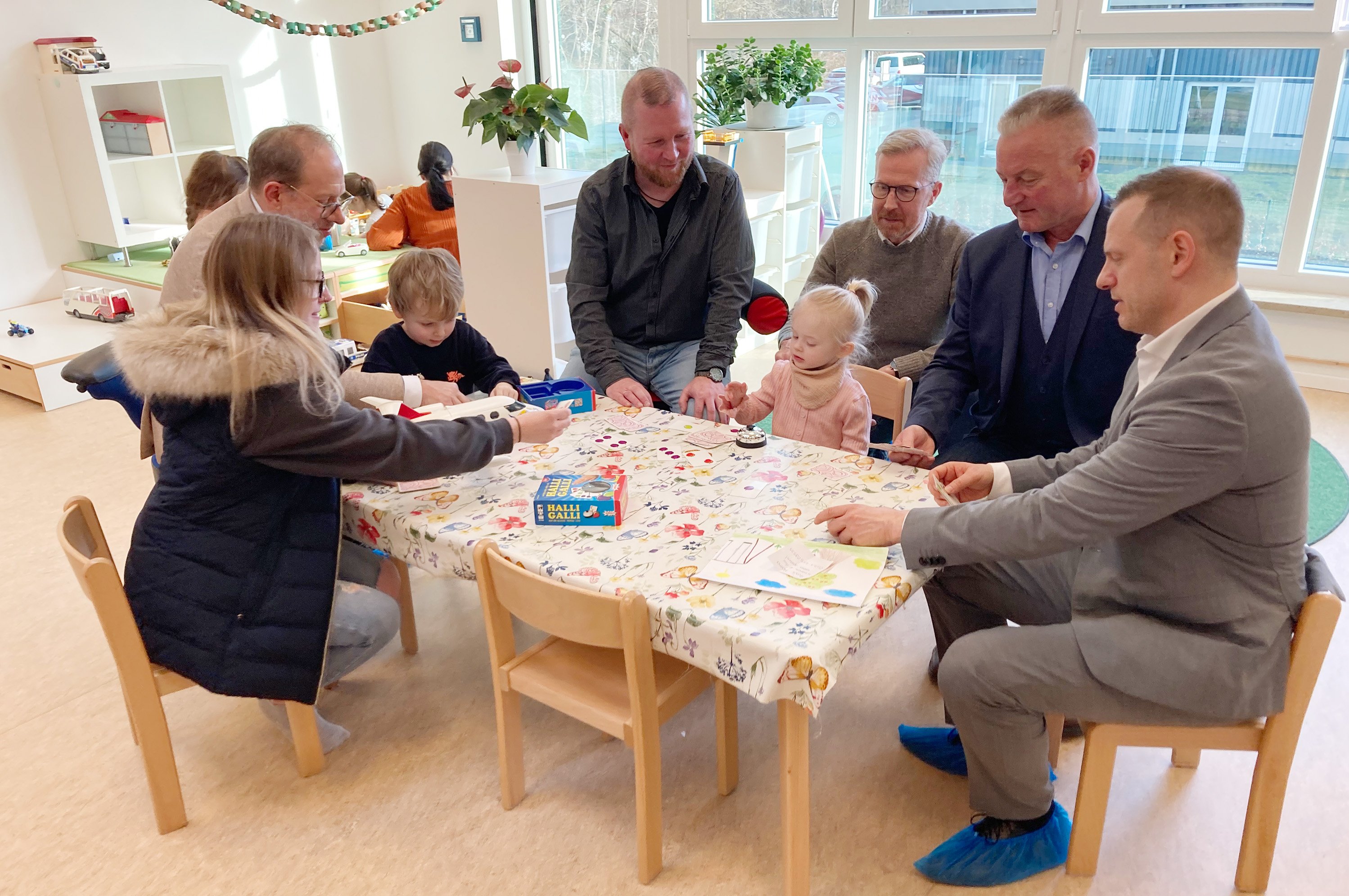 Erwachsene und Kinder sitzen an Kindermöbeln und basteln.