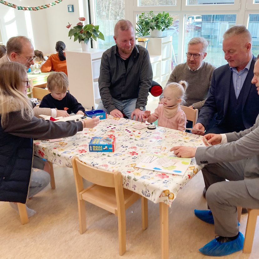 Erwachsene und Kinder sitzen an Kindermöbeln und basteln.